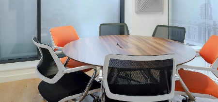 A round, wooden table with six office chairs