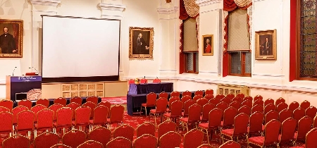 A conference room with rows of seating and a blank projection screen
