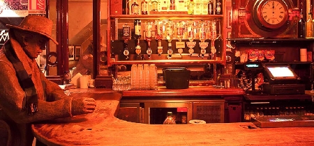 A bar counter with a life-sized sculpture of a patron